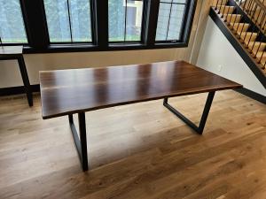 Walnut dining table with steel legs by tall windows, built for a home in Wayzata