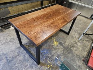 Walnut desk top on black steel legs in the shop by Four Fields Furniture, Minneapolisâ€“St. Paul