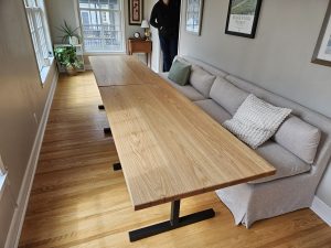 Long oak dining table with bench seating along a sofa, custom made in Minneapolisâ€“St. Paul