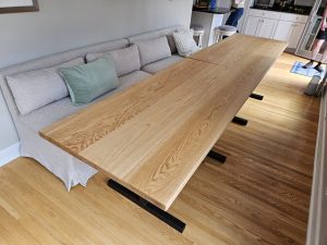 Oak dining table on a black steel base beside a sofa banquette, Minneapolisâ€“St. Paul
