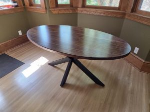 Oval walnut kitchen table on a black spider base by Four Fields Furniture in Minneapolis–St. Paul