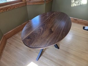 Oval walnut kitchen table on a black steel spider base, handmade in Minneapolis–St. Paul