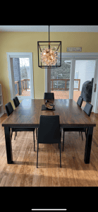 Long walnut dining table set with black chairs and pendant lighting, Minneapolis–St. Paul