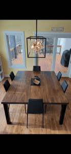 Dark walnut dining table under a geometric pendant light, handmade in Minneapolis–St. Paul
